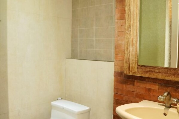 A bathroom with a toilet, sink, and mirror.
