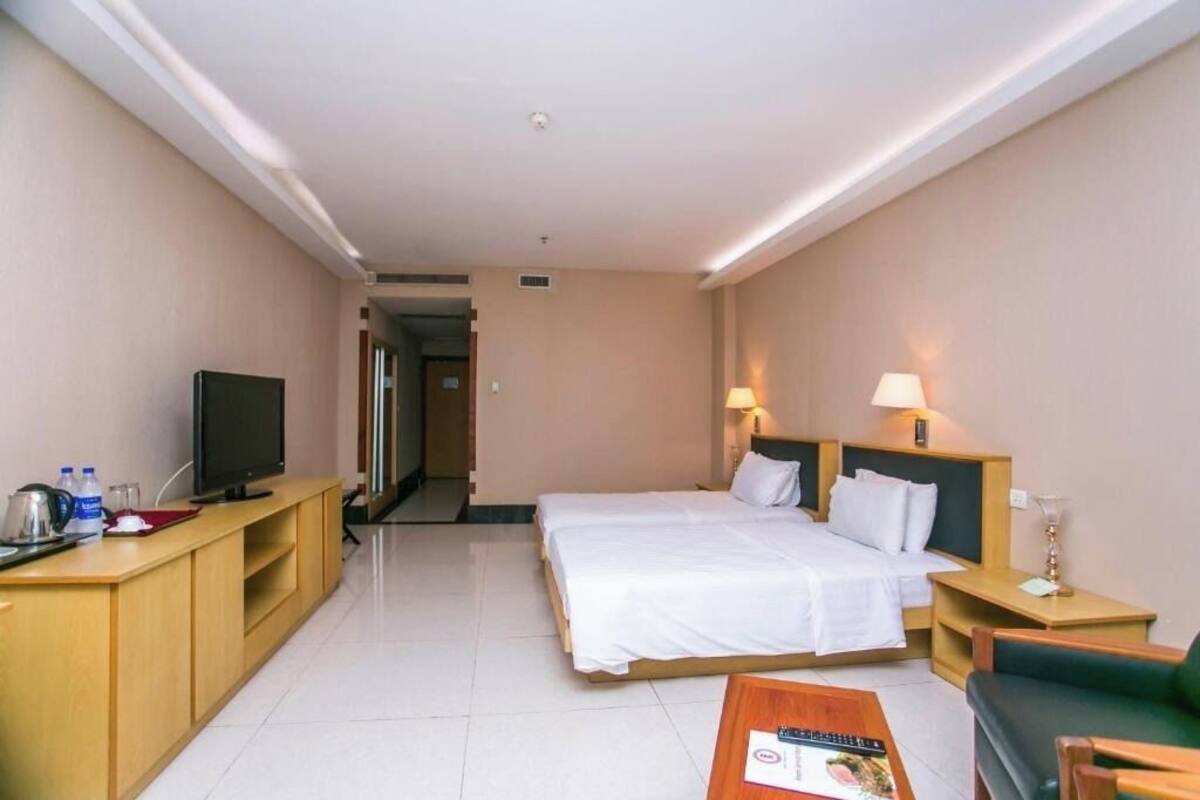 A hotel room with a bed, a TV, a desk with a computer, and a coffee table.