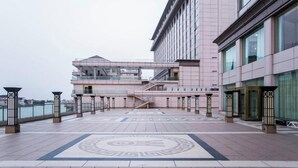 Un bâtiment moderne doté d’une façade en verre, d’un escalier central et d’un sol à motifs.