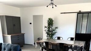 Un salon moderne avec un canapé bleu, une table à manger avec des chaises, une plante en pot et un meuble gris.