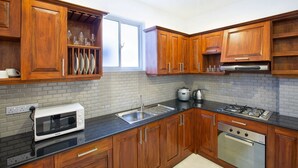 A modern kitchen with wooden cabinets, a built-in oven, a microwave, and a sink.