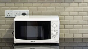 A kitchen with wooden cabinets, a microwave, and a wine rack.