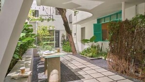 A modern courtyard with a glass table, seating, and greenery. - Express by M Village Tran Quoc Thao, a brand of Modern Village Lifestyle (Ho Chi Minh City)