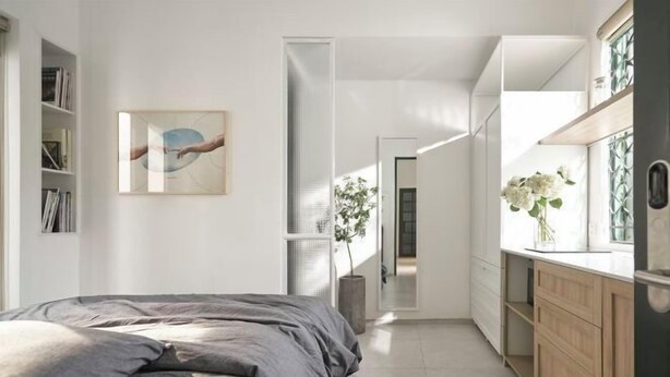 A modern bedroom with a large bed, a bedside bookshelf, and a painting on the wall. - Express by M Village Tran Quoc Thao, a brand of Modern Village Lifestyle (Ho Chi Minh City)