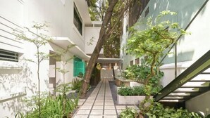 A narrow pathway flanked by greenery and white walls, leading to a staircase. - Express by M Village Tran Quoc Thao, a brand of Modern Village Lifestyle (Ho Chi Minh City)