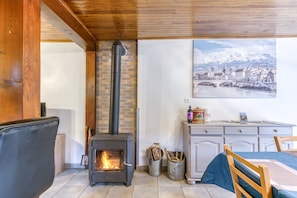 Une pièce avec un poêle à bois, une table à manger avec des chaises, un buffet et un tableau encadré au mur.