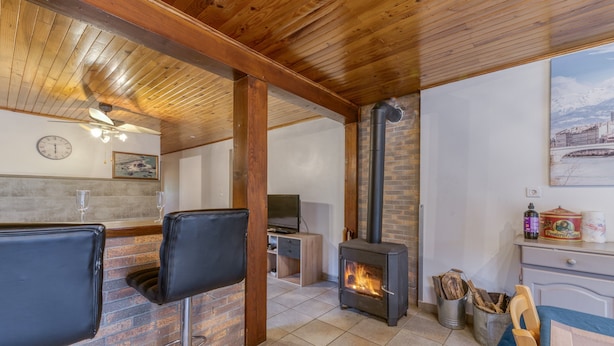 Une pièce chaleureuse avec une cheminée, un plafond en bois et un téléviseur.