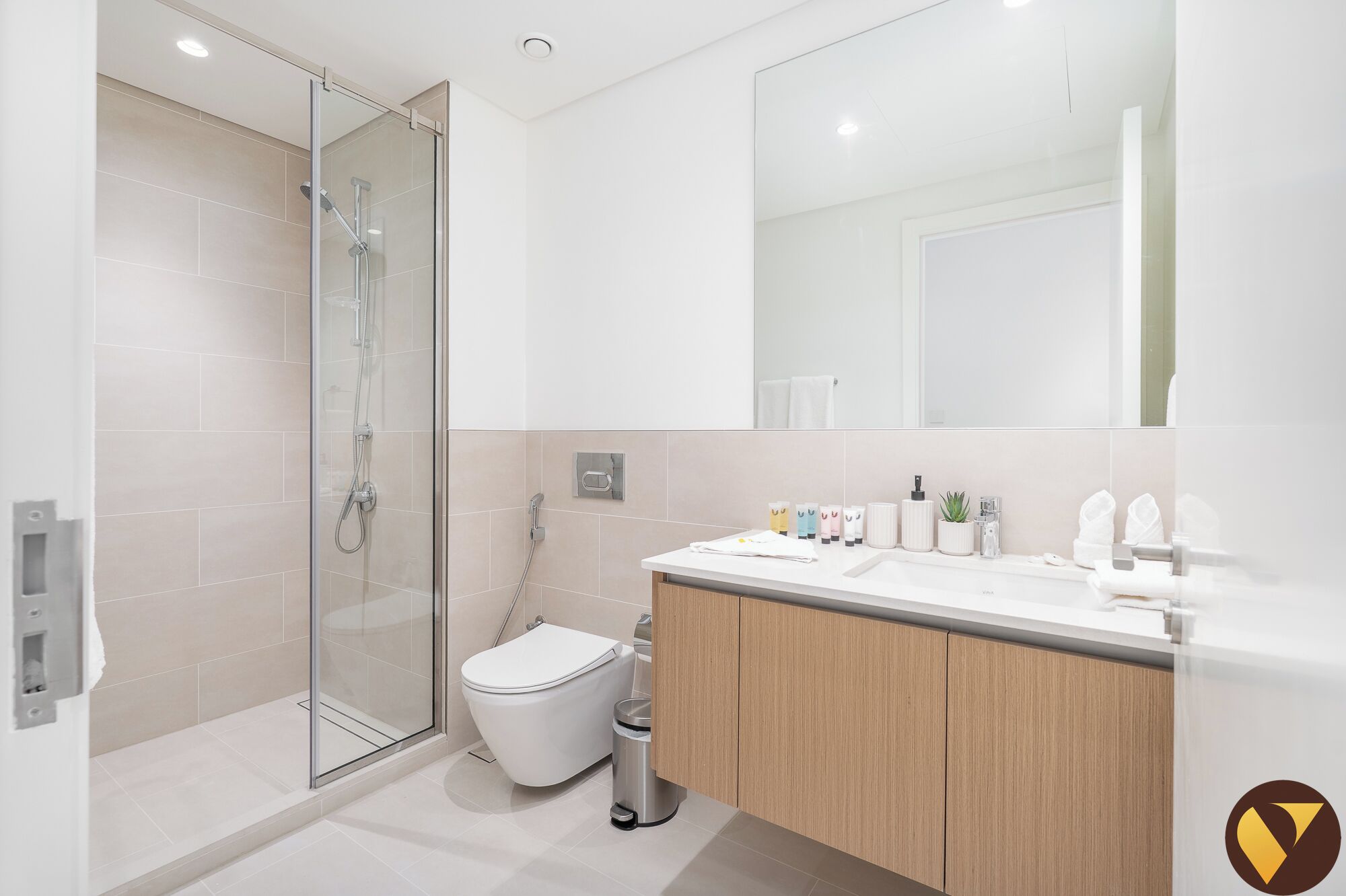 A modern bathroom with a glass-enclosed shower, a toilet, and a vanity with a mirror.