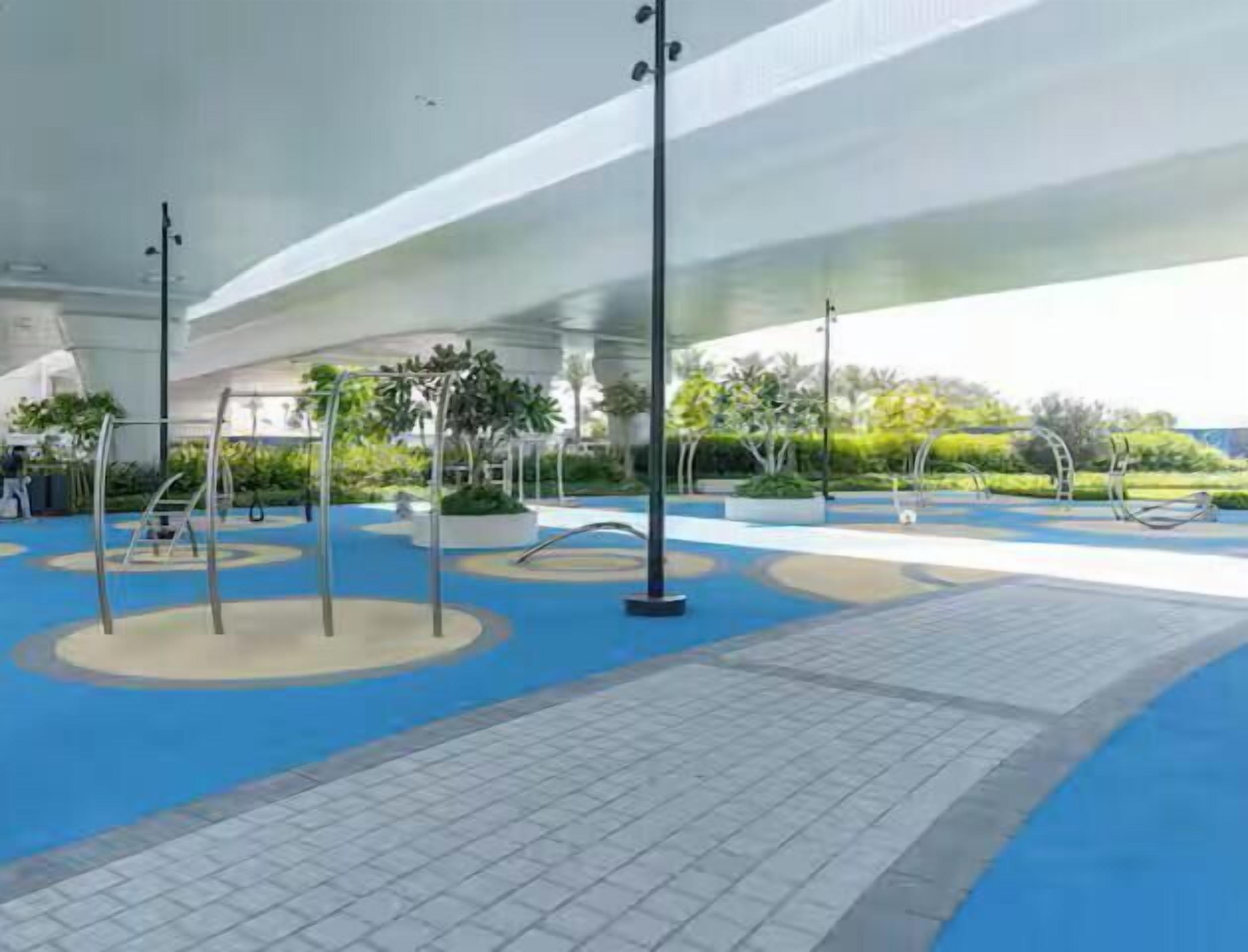An outdoor area with exercise equipment, a covered walkway, and landscaped greenery.