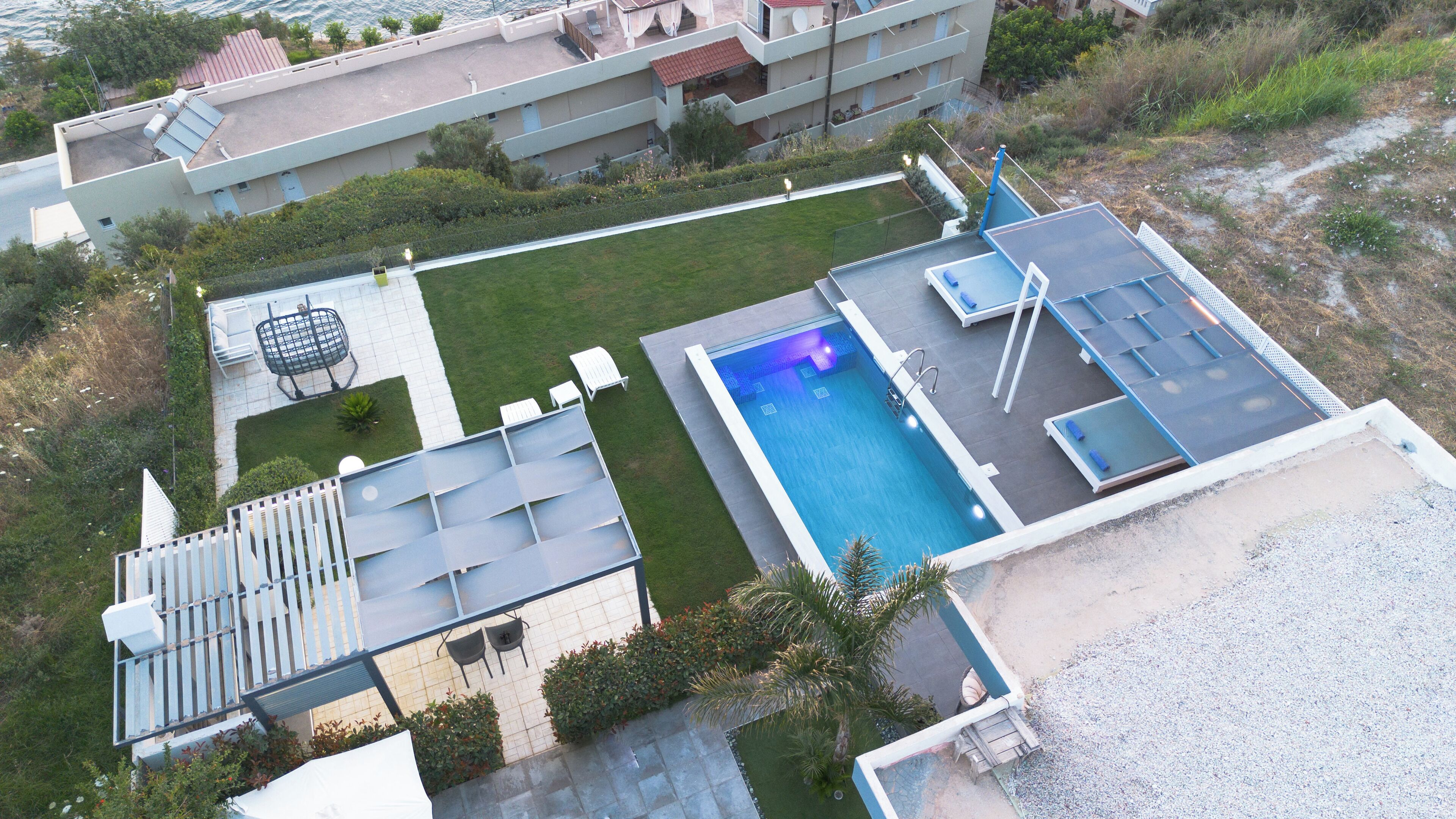 An aerial view of a residential area with a swimming pool, outdoor seating, and a rooftop deck.