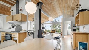 Eine moderne Küche mit Holzausstattung, einem großen Esstisch und Pendelleuchten.