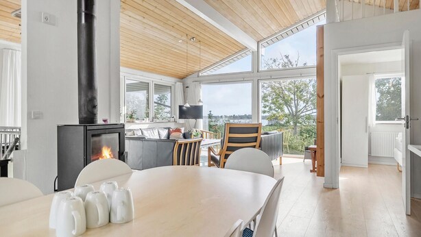 Eine moderne Küche mit Kaminofen, großen Fenstern und einem Essbereich mit Blick ins Freie.