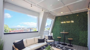 Un espace de détente moderne comprenant un canapé, des fauteuils, une table basse et un panneau lumineux au néon sur lequel on peut lire : « Nashville, capitale de la musique ».