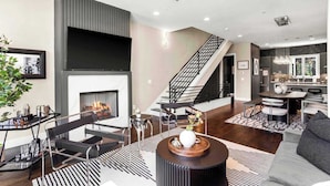 Un salon moderne avec une cheminée, un escalier et un coin repas.