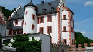 A castle-like building with multiple towers and a turret, featuring a mix of white and red walls, and a grey roof.