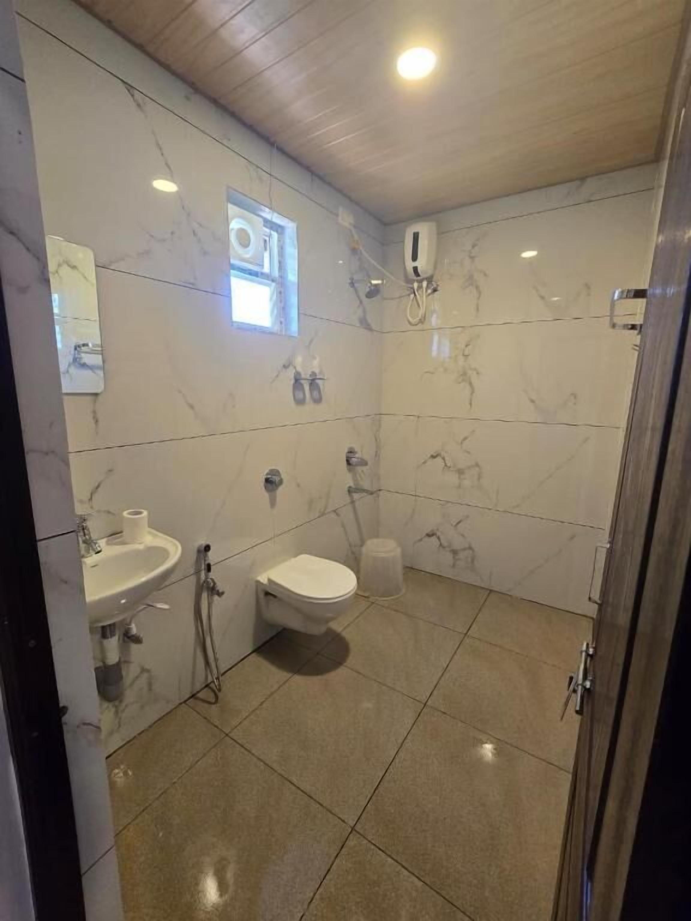 A bathroom with a marble wall, a sink, a toilet, and a bidet.