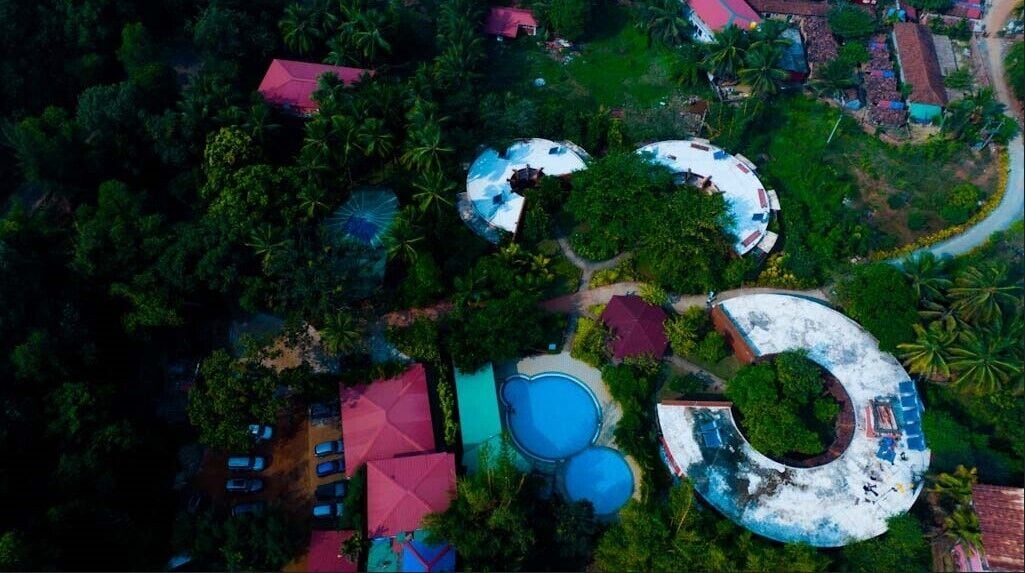 An aerial view of a resort with multiple buildings, a swimming pool, and lush greenery.