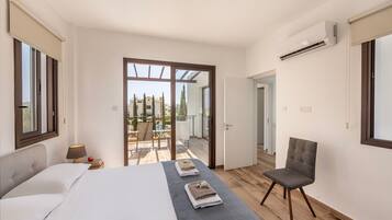 A bedroom with a bed, a chair, and a view of a pool and buildings outside.