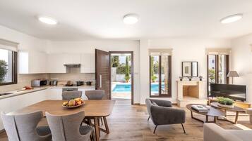 A modern apartment with a kitchen, dining area, and living room. It features a pool, a fireplace, and a TV.