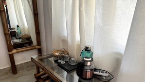 A glass-top table with a coffee maker, salt and pepper shakers, and a glass. - Bonsai Eco Village (Kamalganj)