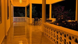 A corridor with tiled flooring, a patterned railing, and a view of the night sky through large windows. - Bonsai Eco Village (Kamalganj)