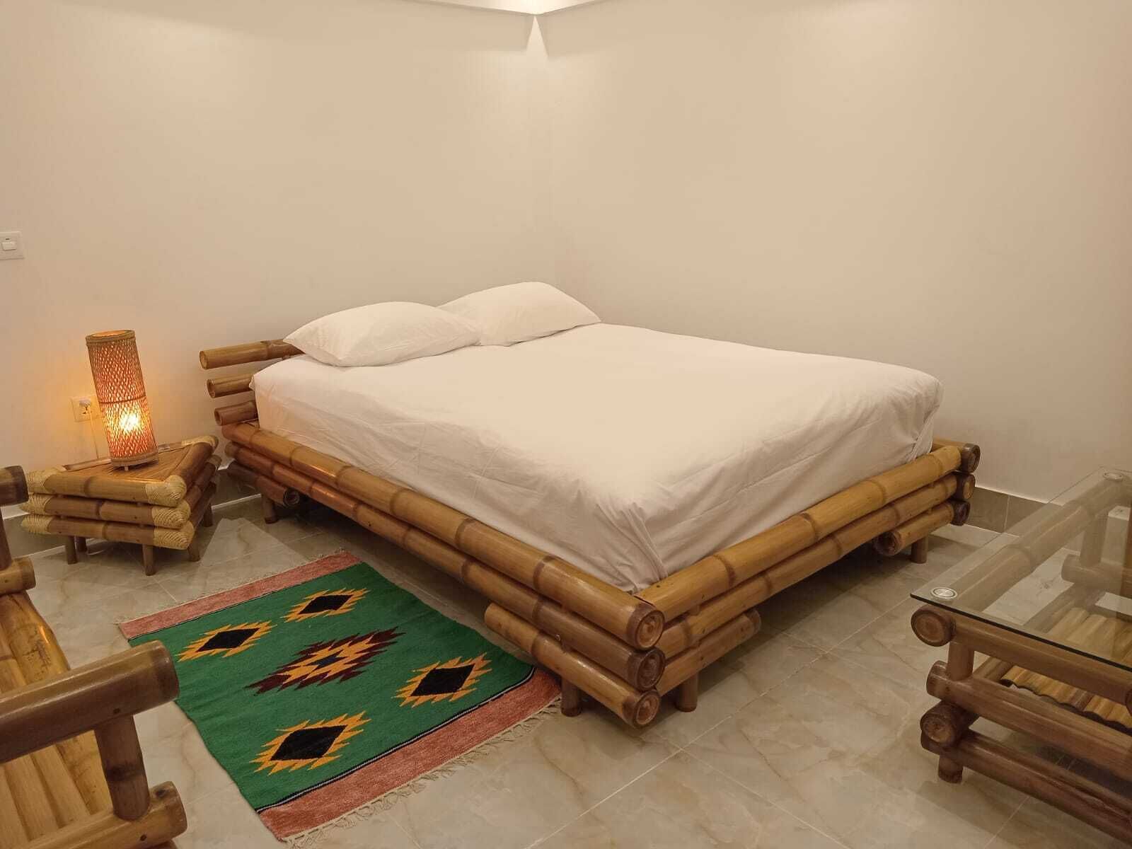 A room with a bed, a nightstand, a lamp, a chair, and a table.