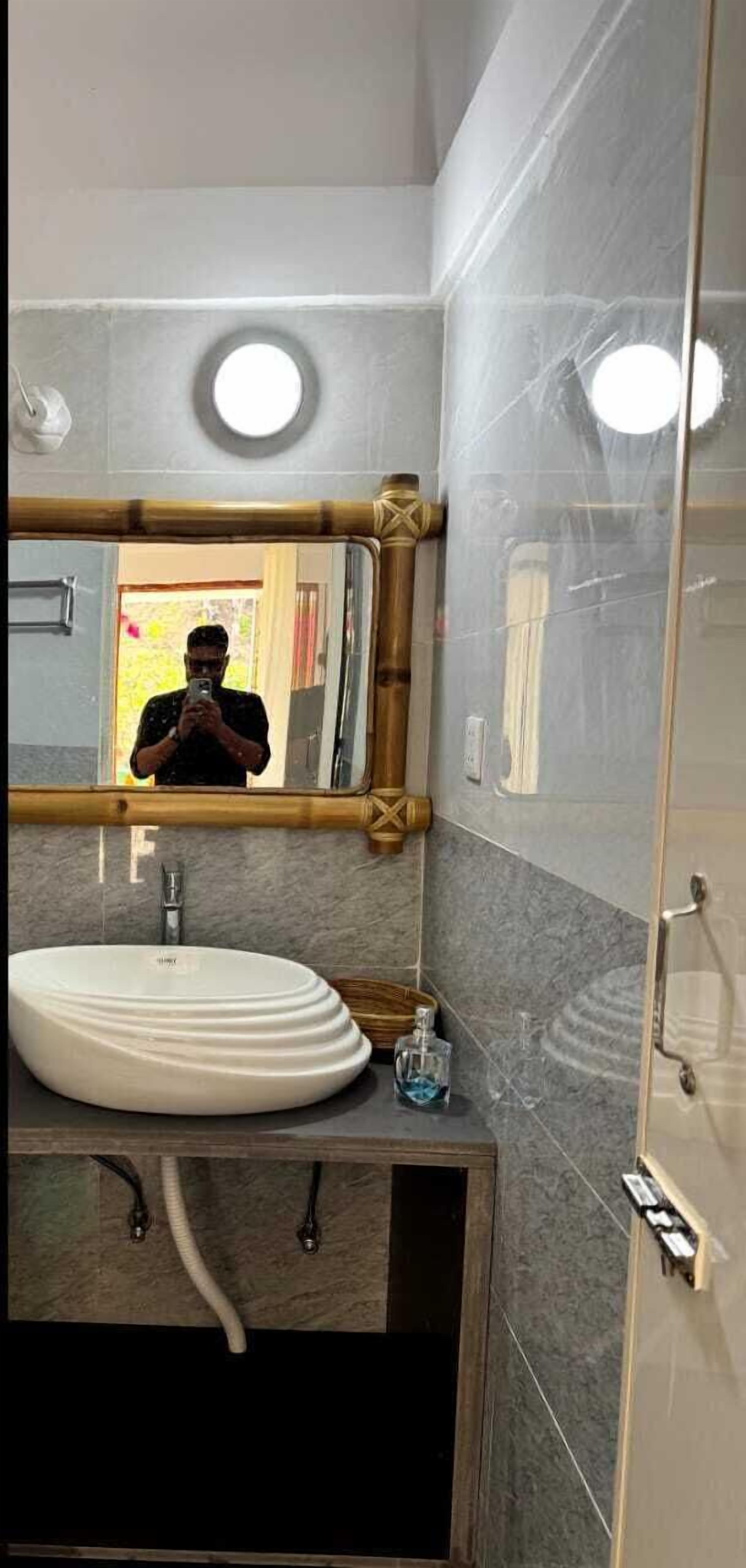 Un baño con un espejo redondo, un lavabo blanco y una zona de ducha.