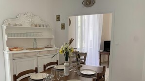 A dining area with a white cabinet, a vase with flowers, and a table set for four.