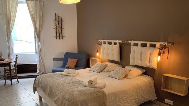 A bedroom with a bed, bedside tables, a chair, a lamp, and a window with curtains.