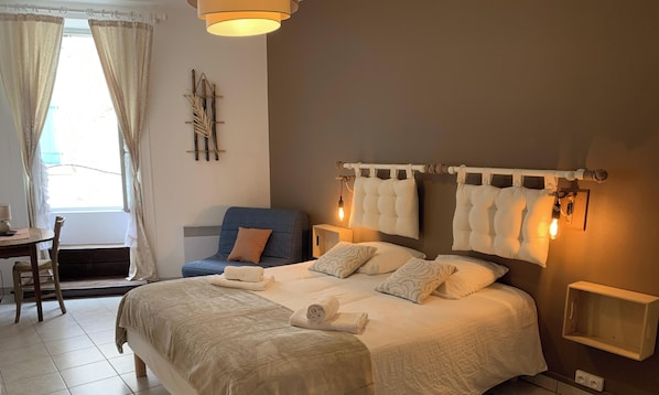 Une chambre à coucher avec un lit, des tables de chevet, une chaise et une fenêtre avec des rideaux.