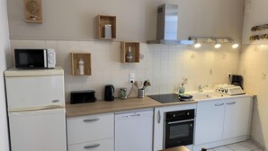 A modern kitchen with white cabinetry, a microwave, a toaster, a kettle, and a built-in oven.