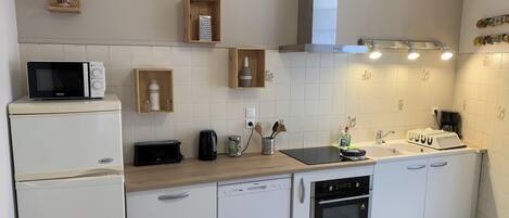 A modern kitchen with white cabinetry, a microwave, a toaster, a kettle, and a built-in oven.