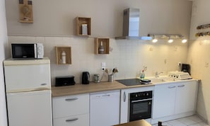 Et moderne køkken med hvide skabe, en mikrobølgeovn, en brødrister, elkedel og et indbygget ovn.