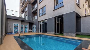 A modern building with a swimming pool, changing rooms, and a balcony. - Spacious Loft in Lavington With Pool + Gym & Playground (Nairobi)