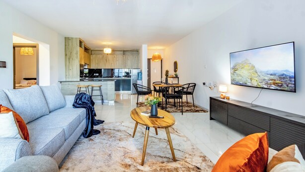 A modern living room with a sofa, coffee table, and a TV mounted on the wall. - Spacious Loft in Lavington With Pool + Gym & Playground (Nairobi)