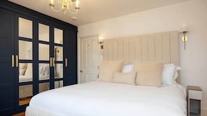 A bedroom with a large bed, a wardrobe with mirrored doors, and a chandelier.