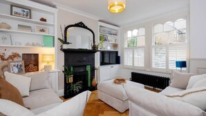 A living room with a fireplace, white sofas, a TV, and a bookshelf.