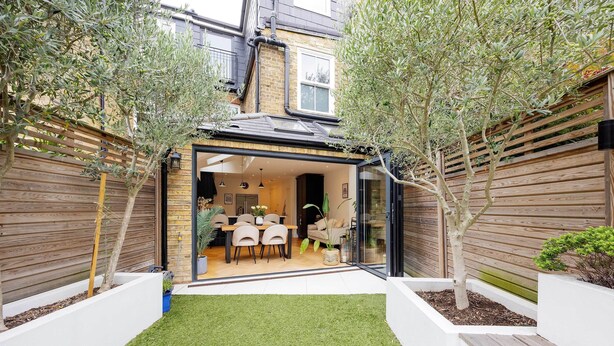 A modern house with a patio, a dining area, and a small garden.