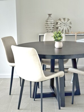 Mesa de jantar com quatro cadeiras, um vaso com planta e objetos decorativos.