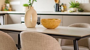 A modern kitchen with a white vase and wooden bowl on the counter. - Deluxe Two-bedroom Apartment (Trachoni)