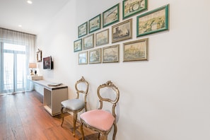 A room with a desk, two chairs, and a wall adorned with framed pictures.