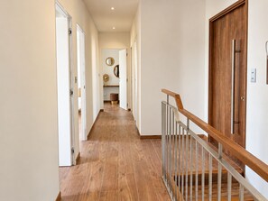 A hallway with wooden flooring, white walls, and a wooden door with a metal handle.