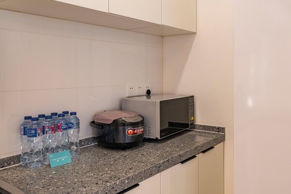 A kitchen counter with bottled water, a coffee maker, and a microwave. - Tyms Bright 2BR 1BA Apt Xuhui Center (Shanghai)