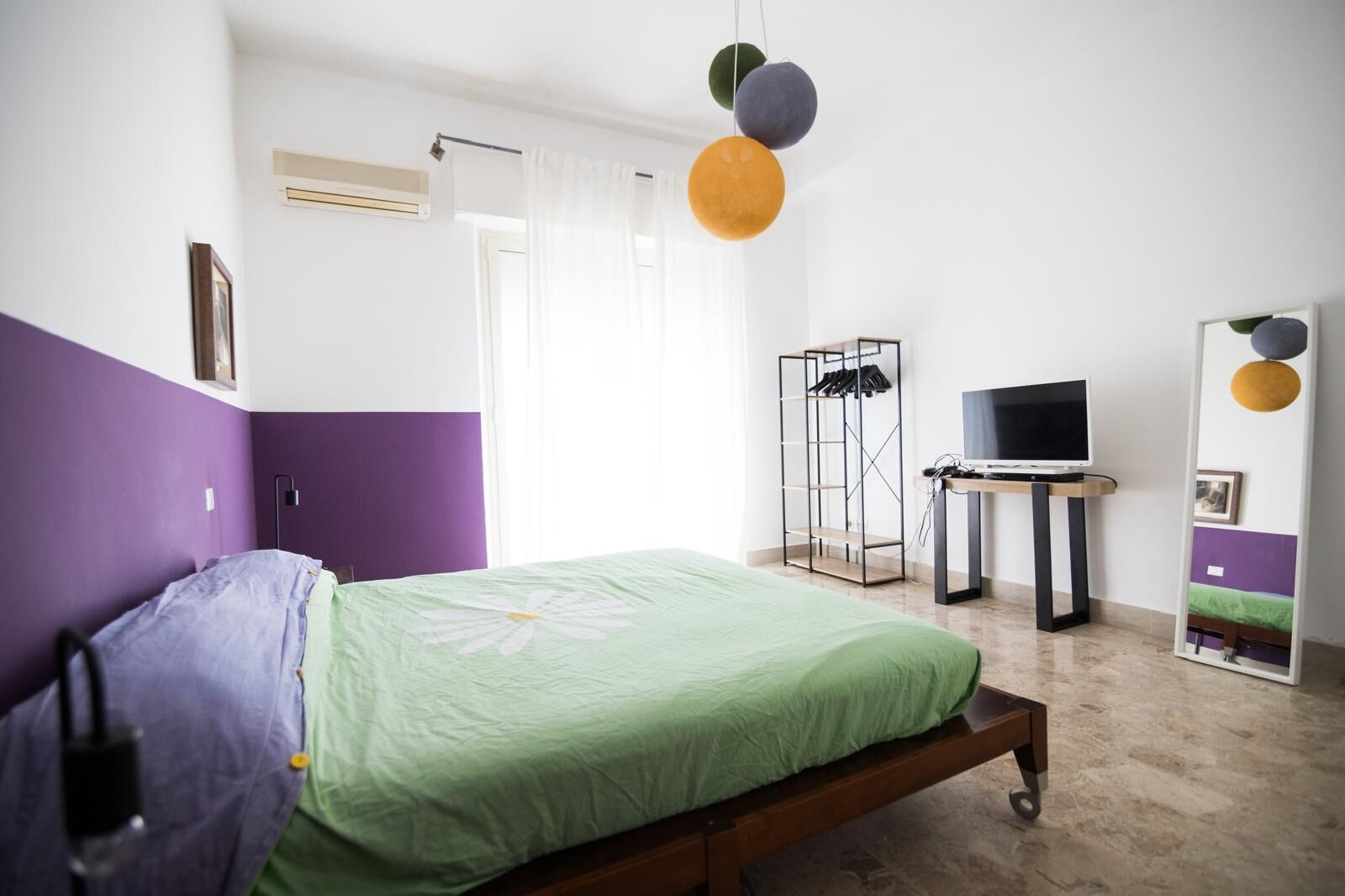 Une chambre à coucher avec un lit, une télévision, une armoire et un miroir.