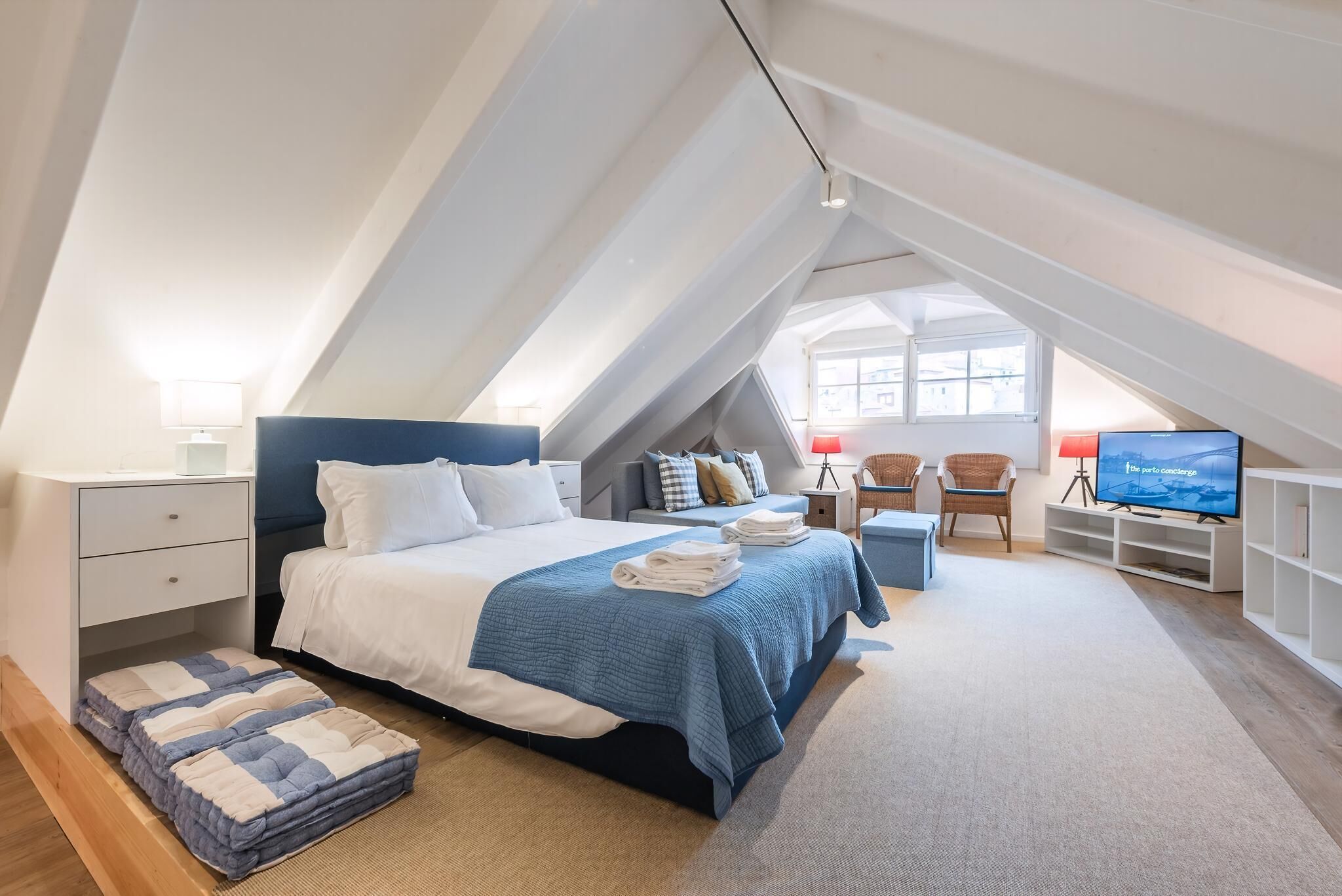 A modern bedroom with a bed, bedside tables, a TV, and a window.