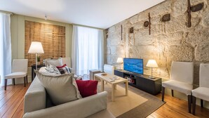 Ein modernes Wohnzimmer mit einer Wand aus Stein, einem Flachbildfernseher und einer gemütlichen Sitzecke.