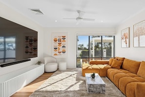 A modern living room with a sectional sofa, a coffee table, and a large flat-screen TV mounted on the wall. - La La Land by Coast Hosting (Kariong)
