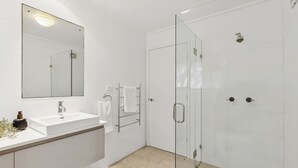 A modern bathroom with a glass-enclosed shower, a white sink, and a large mirror. - Ocean Views Every Room. 100m to Beach. Sleeps 13 (North Avoca)