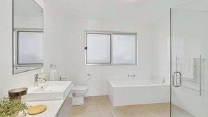 A modern bathroom with a white sink, toilet, and bathtub.