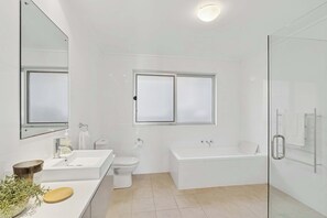 Un baño moderno con lavamanos, inodoro y bañera blancos.